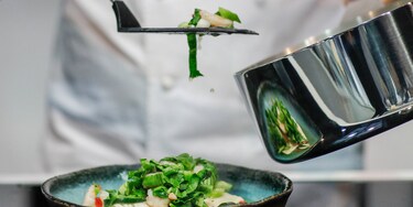 Um chefe de cozinha a empratar um prato com o tacho de molhos Infinite Chef