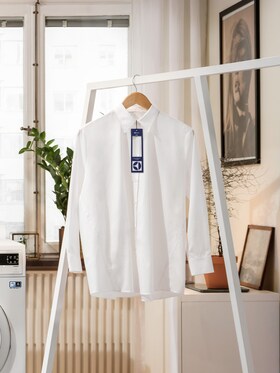 Camisa branca com uma etiqueta de lavandaria numa sala de estar