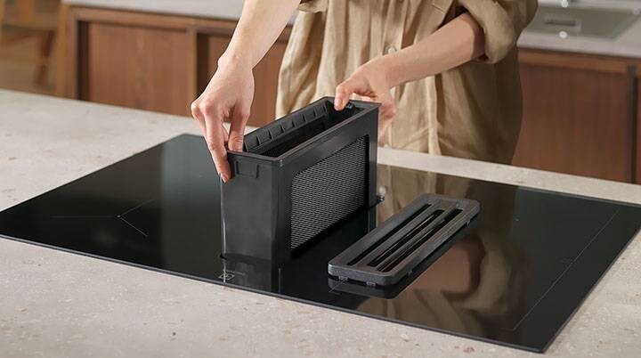 Mãos a colocar o filtro de gordura do exaustor